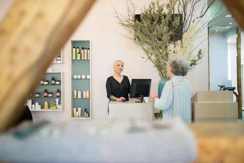 A hairdresser speaking with a client at a salon desk
