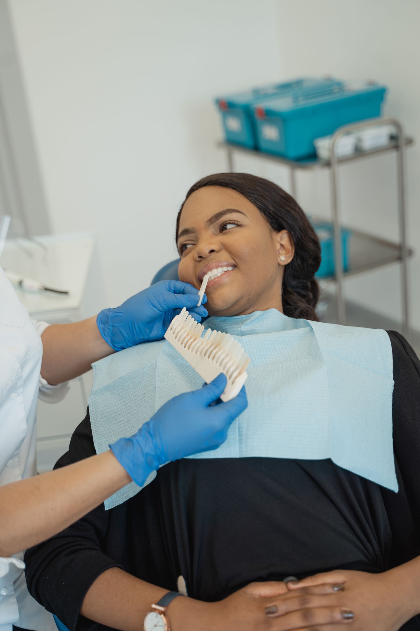 Dentist helping a reclining patient choose a tooth shade.