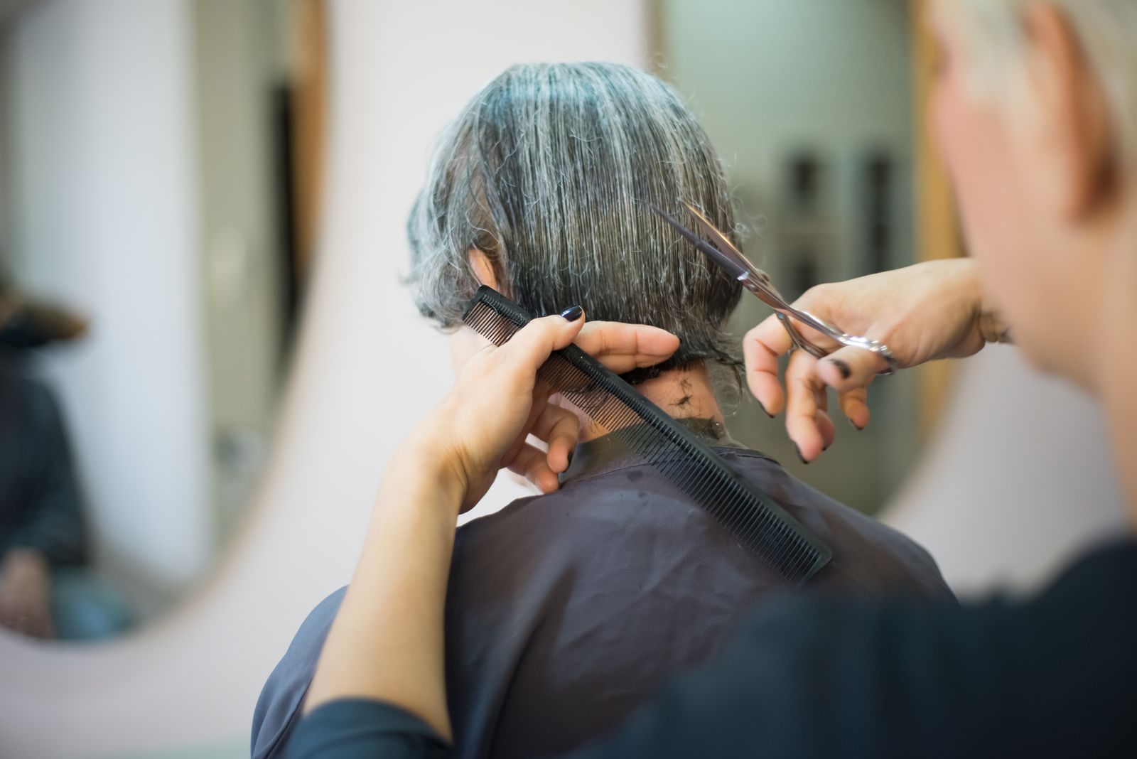 A stylist cutting a client's grey hair