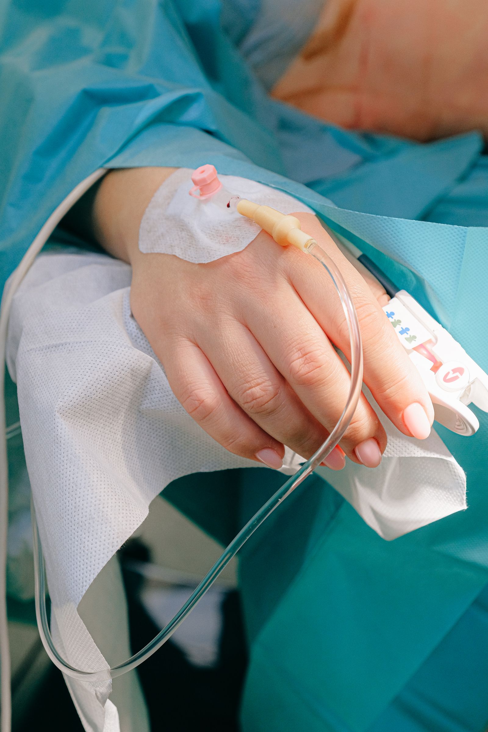 Close view of an IV line attached to a patient's hand.