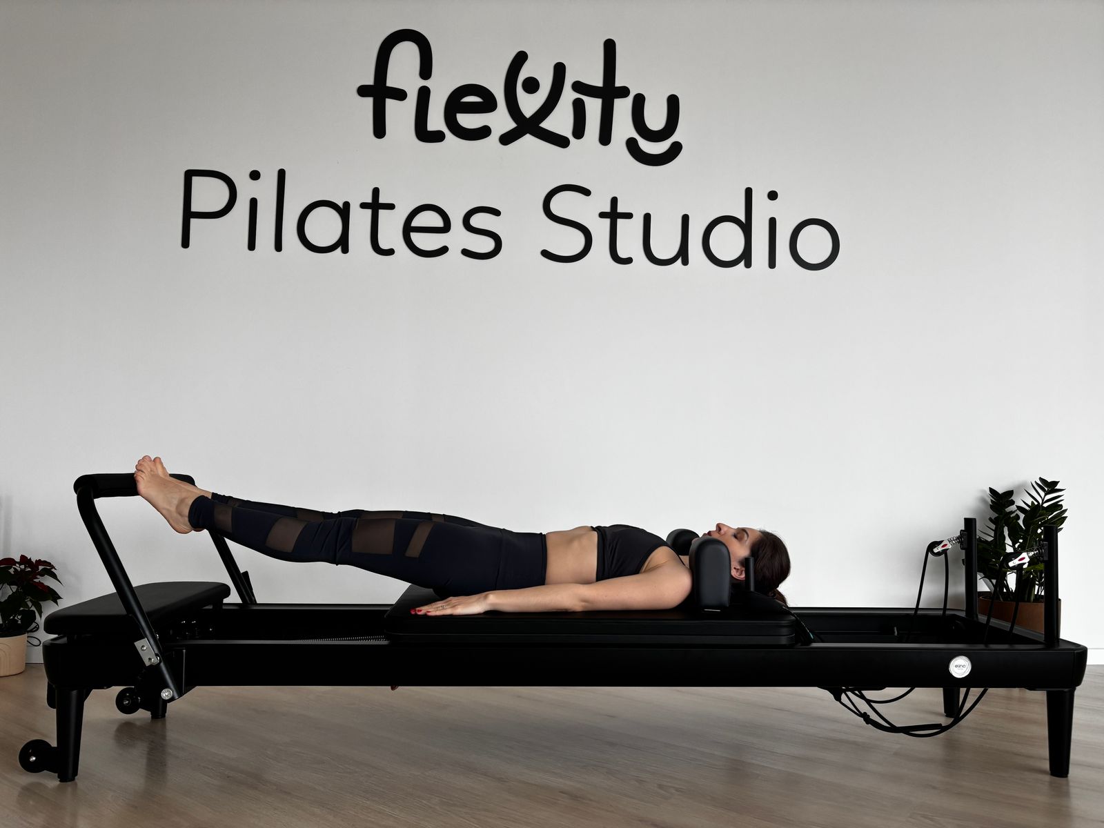 Woman exercising on a reformer. Lower crop minimizes studio wall branding.