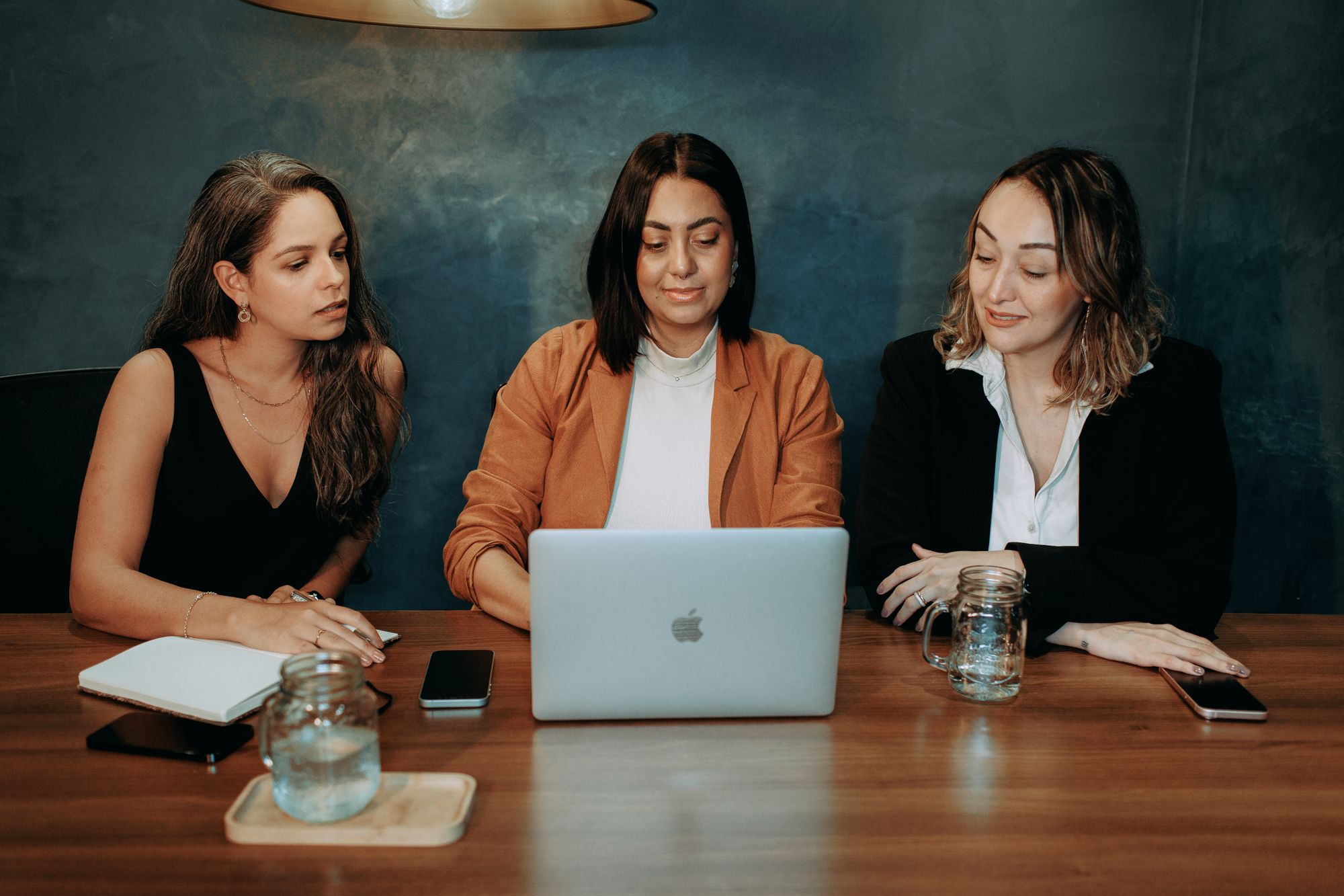 Three women discussing work around a laptop at a table