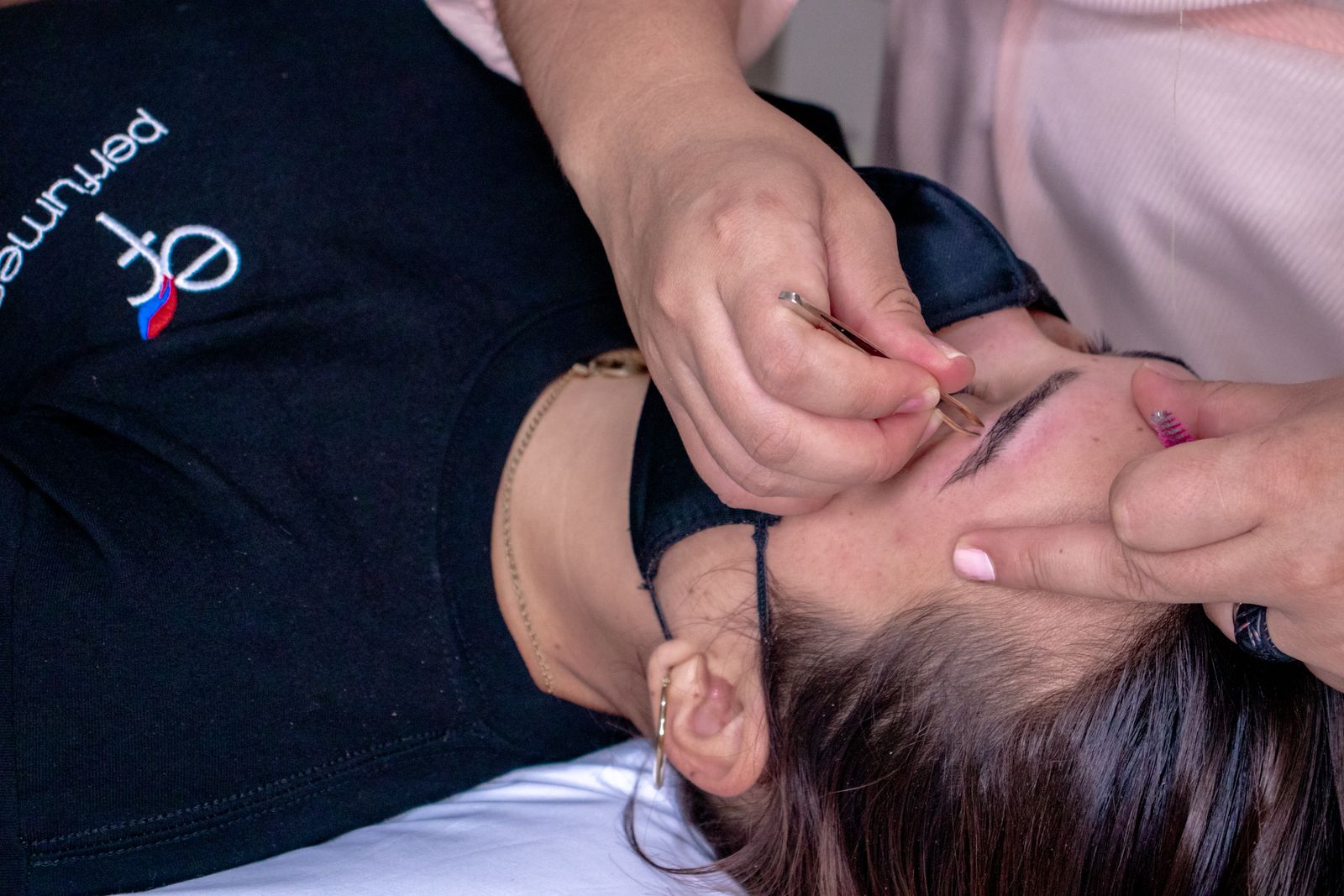 A beauty professional styling a client’s eyebrows.